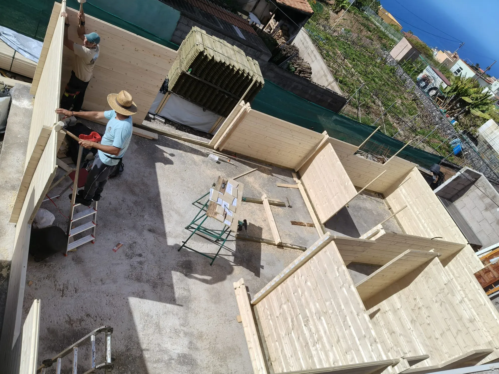 A crew assembling a Satus Baltic log house kit on a foundation